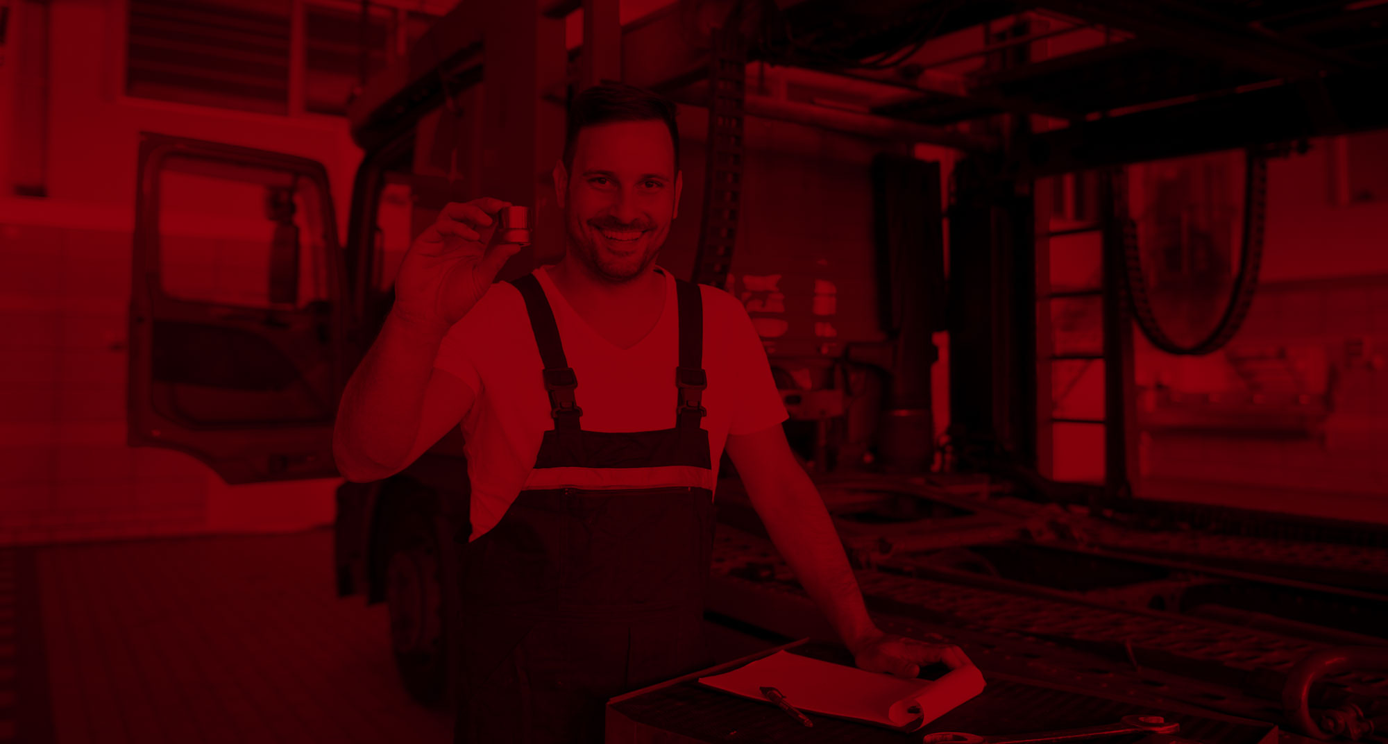 Mechaniker hält Werkzeugnuß hoch und lächelt