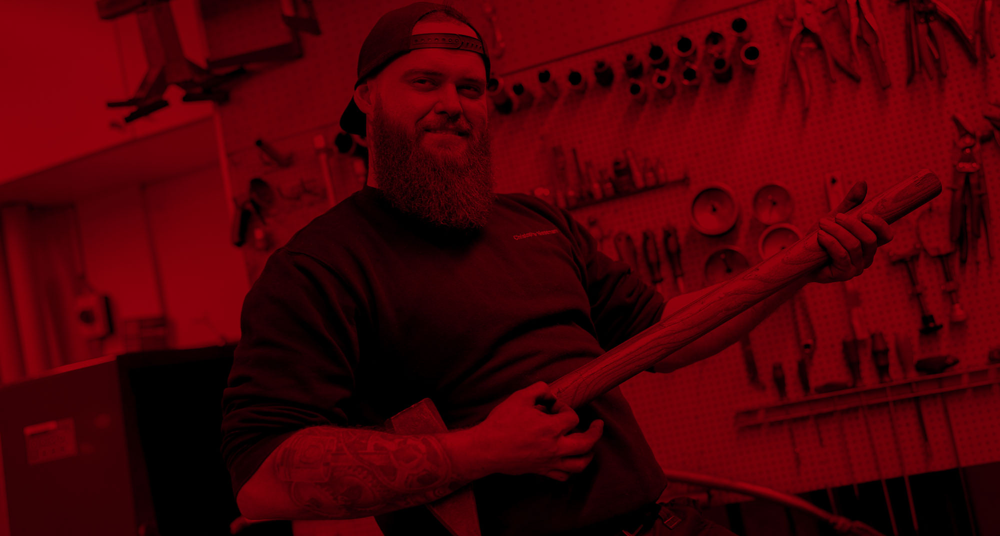 Mechaniker mit Bart spielt Luftgitarre mit Vorschlaghammer